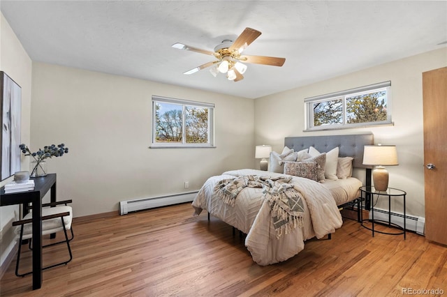 bedroom featuring light wood-type flooring, ceiling fan, and baseboard heating