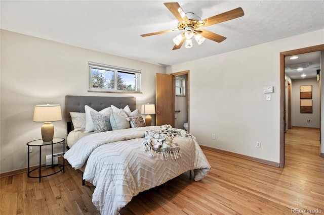 bedroom with baseboard heating, ceiling fan, and light hardwood / wood-style floors