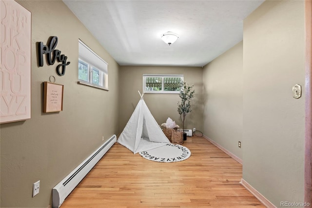 recreation room with baseboard heating and light hardwood / wood-style flooring