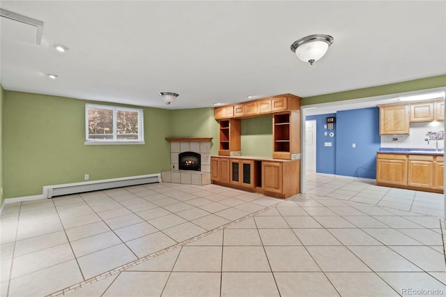 unfurnished living room with a tiled fireplace, a baseboard radiator, sink, and light tile patterned floors