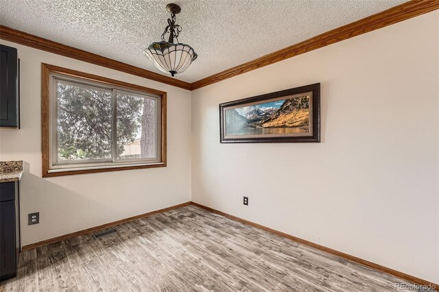 1824 S Granby St, Aurora, CO 80012 - unfurnished dining area featuring light wood finished floors, a textured ceiling, baseboards, and ornamental molding