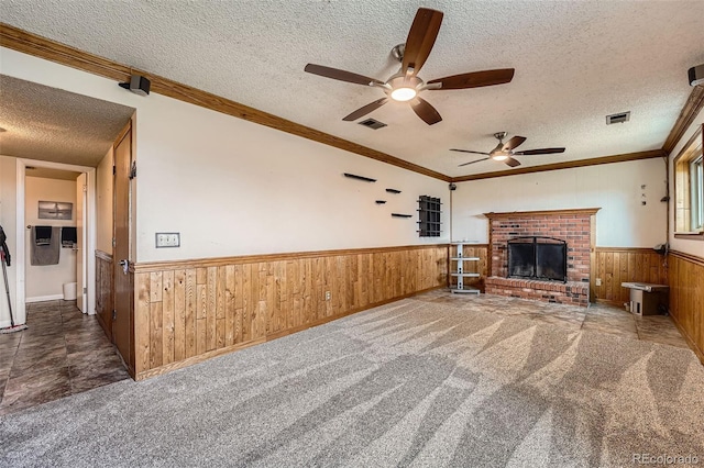 1824 S Granby St, Aurora, CO 80012 - unfurnished living room featuring a wainscoted wall, wood walls, a textured ceiling, a ceiling fan, and a brick fireplace