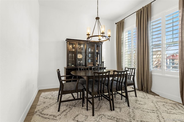 dining space featuring a chandelier, baseboards, and wood finished floors