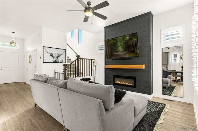 living room with a ceiling fan, wood finished floors, stairway, a fireplace, and baseboards