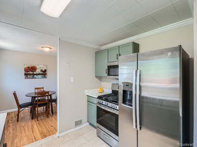 3750 S Galapago St, Englewood, CO 80110 - kitchen with appliances with stainless steel finishes, green cabinetry, ornamental molding, light countertops, and light tile patterned floors