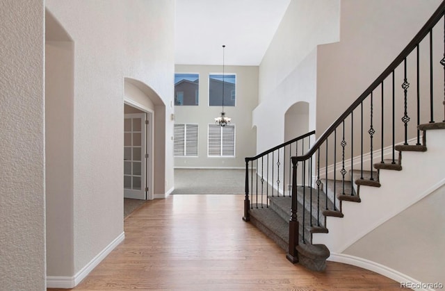 foyer entrance with an inviting chandelier, light hardwood / wood-style floors, and a high ceiling