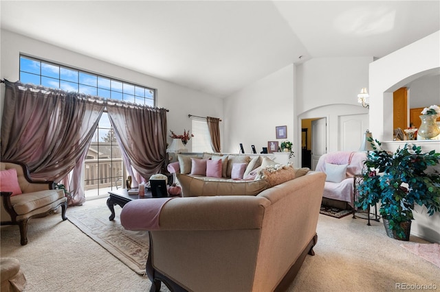 living room with light carpet, high vaulted ceiling, and arched walkways