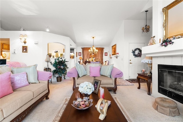 carpeted living area featuring vaulted ceiling, a notable chandelier, and a tile fireplace