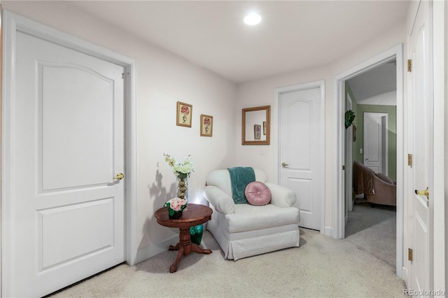 living area with baseboards and light colored carpet