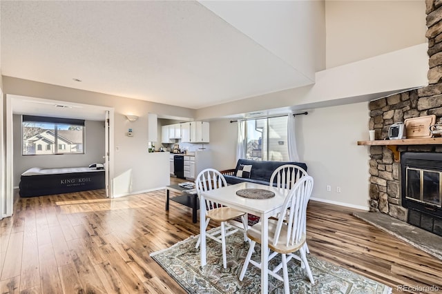 dining area featuring a stone fireplace, plenty of natural light, and light hardwood / wood-style flooring