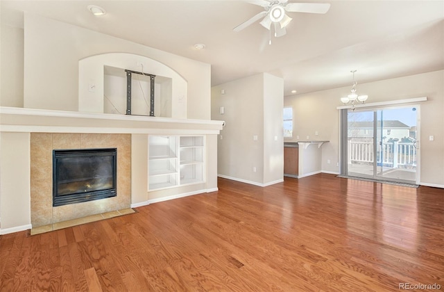 unfurnished living room with a fireplace, hardwood / wood-style floors, and ceiling fan with notable chandelier