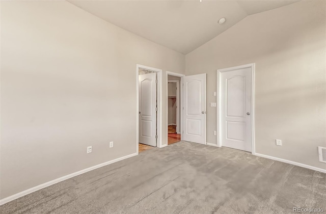 unfurnished bedroom featuring lofted ceiling and light carpet