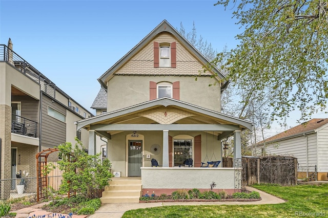 view of front of house featuring a porch, stucco siding, and fence