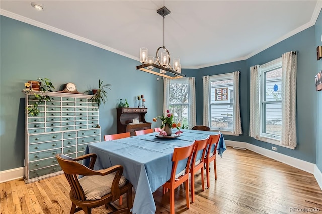 dining room featuring baseboards, crown molding, light wood finished floors, and an inviting chandelier