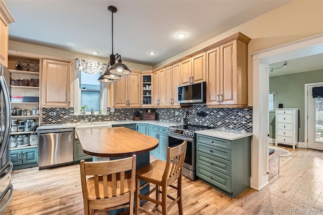kitchen featuring light brown cabinetry, stainless steel appliances, light countertops, light wood-style floors, and tasteful backsplash