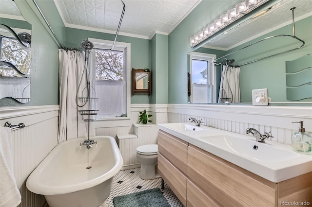 bathroom with plenty of natural light, a wainscoted wall, a freestanding tub, and a sink