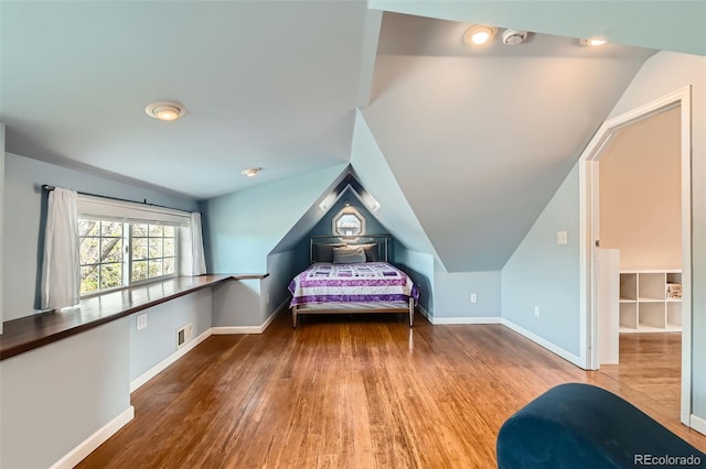 bedroom featuring lofted ceiling, baseboards, and wood finished floors