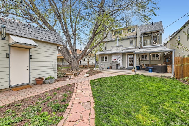 rear view of property with fence, a lawn, roof with shingles, and a patio