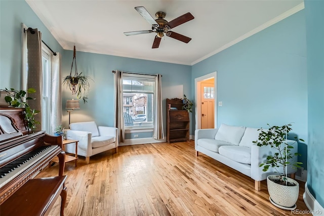 living area with ceiling fan, baseboards, wood finished floors, and ornamental molding