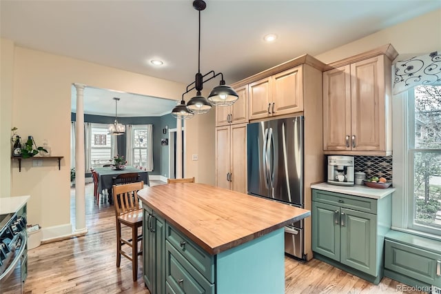 kitchen with plenty of natural light, an inviting chandelier, decorative columns, wood counters, and appliances with stainless steel finishes