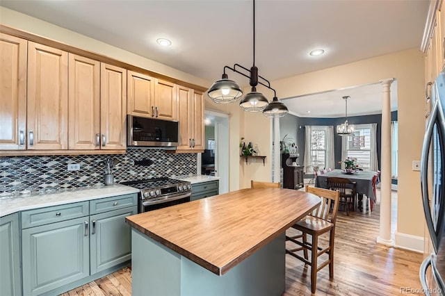 kitchen with light wood finished floors, stainless steel appliances, butcher block counters, decorative light fixtures, and tasteful backsplash