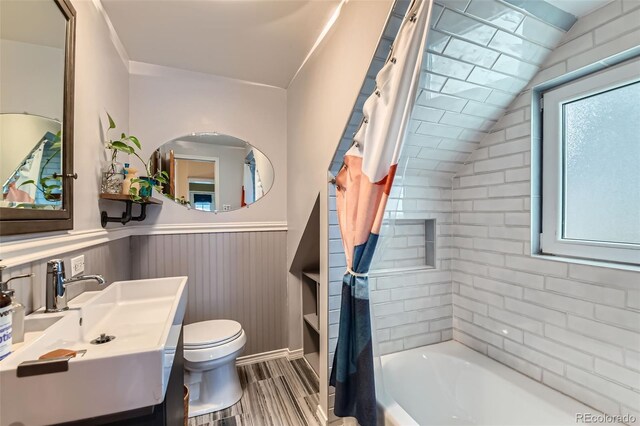 bathroom featuring toilet, wainscoting, shower / tub combo, wood finished floors, and vanity