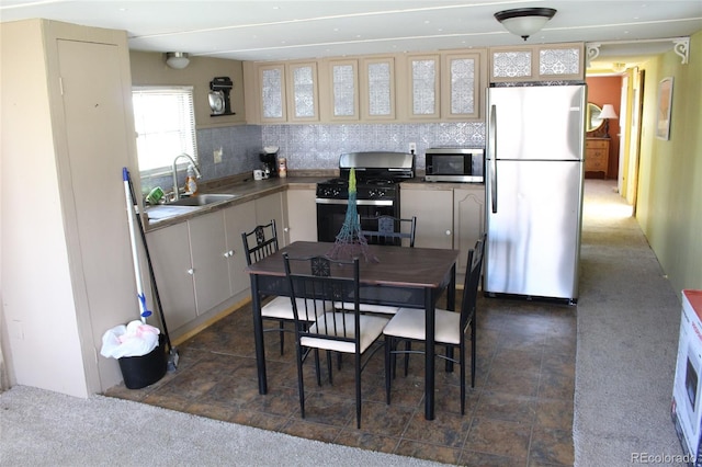 kitchen with backsplash, sink, appliances with stainless steel finishes, and dark colored carpet