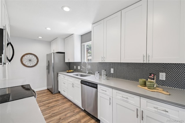 112 S Hooker St, Denver, CO 80219 - kitchen with appliances with stainless steel finishes, tasteful backsplash, white cabinets, wood finished floors, and recessed lighting