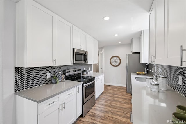 112 S Hooker St, Denver, CO 80219 - kitchen featuring stainless steel appliances, tasteful backsplash, recessed lighting, wood finished floors, and white cabinets