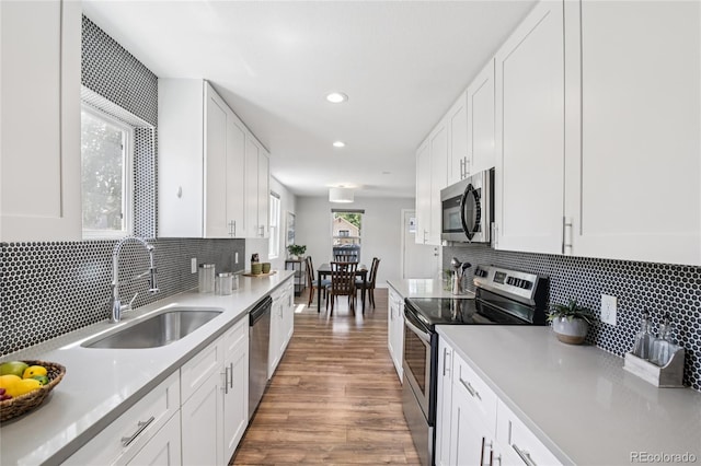 112 S Hooker St, Denver, CO 80219 - kitchen with stainless steel appliances, white cabinetry, wood finished floors, recessed lighting, and light countertops