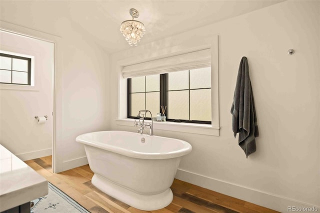 700 Cheyenne St, Golden, CO 80401 - full bath with an inviting chandelier, baseboards, a soaking tub, and wood finished floors
