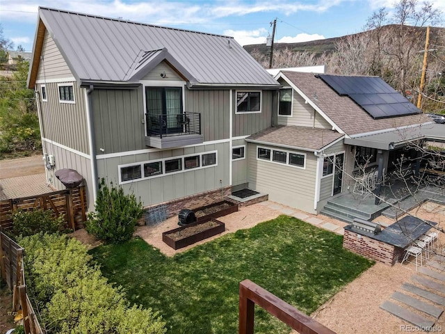 700 Cheyenne St, Golden, CO 80401 - rear view of house with a lawn, roof mounted solar panels, a fenced backyard, a balcony, and a patio