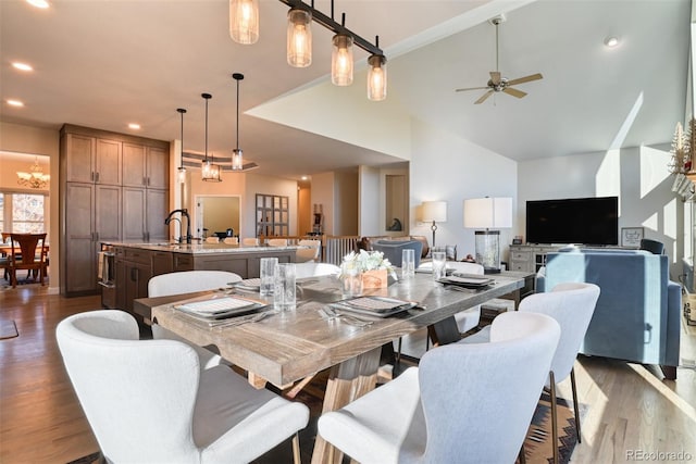 dining space featuring ceiling fan with notable chandelier, dark hardwood / wood-style floors, high vaulted ceiling, and sink