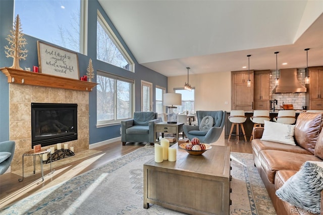 living room featuring a tiled fireplace, light hardwood / wood-style flooring, and lofted ceiling