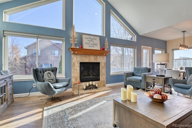 living room featuring a chandelier, light wood-type flooring, a fireplace, and vaulted ceiling