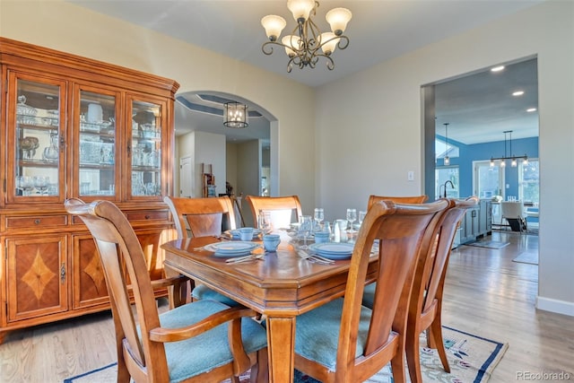 dining room with light hardwood / wood-style floors and an inviting chandelier