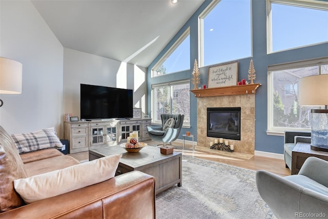 living room with a tile fireplace, high vaulted ceiling, and light hardwood / wood-style flooring