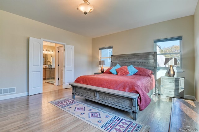 bedroom featuring connected bathroom, hardwood / wood-style floors, and multiple windows