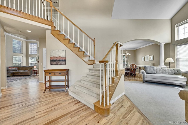 14878 E Aberdeen Ave, Centennial, CO 80016 - staircase featuring a high ceiling, arched walkways, wood finished floors, decorative columns, and a chandelier