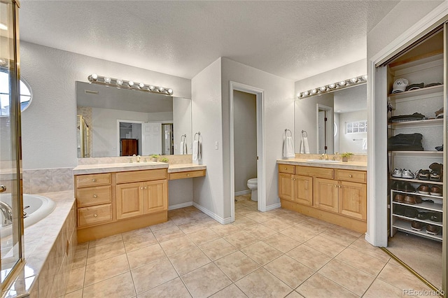14878 E Aberdeen Ave, Centennial, CO 80016 - full bathroom featuring a textured ceiling, tile patterned floors, a garden tub, two vanities, and a walk in closet