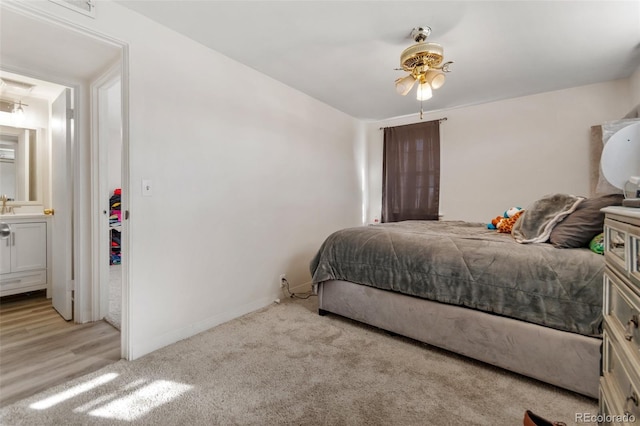 bedroom with light hardwood / wood-style flooring, ensuite bathroom, and ceiling fan