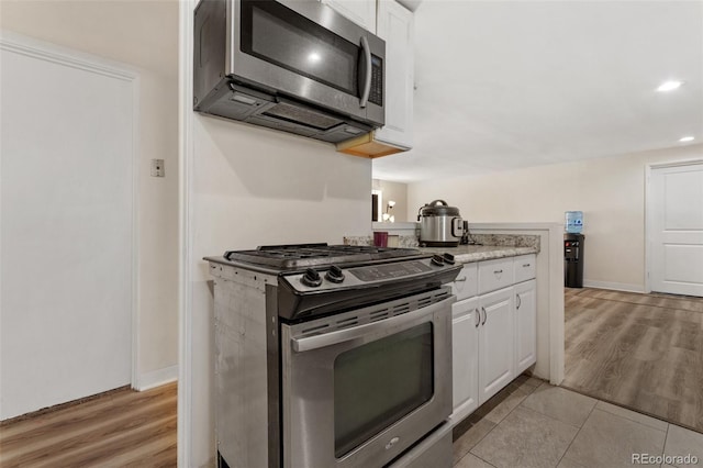 kitchen featuring white cabinets, stainless steel appliances, and light wood-type flooring