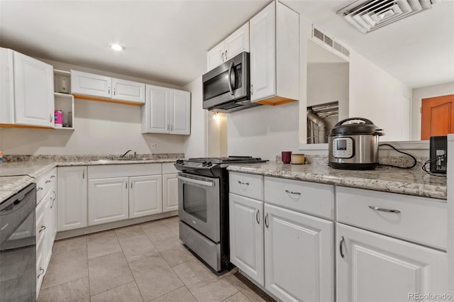 kitchen with light stone countertops, appliances with stainless steel finishes, sink, white cabinetry, and light tile patterned floors