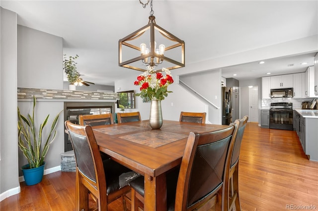 15353 E 98th Pl, Commerce City, CO 80022 - dining space with light wood-type flooring, a chandelier, recessed lighting, and a fireplace