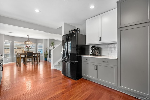 15353 E 98th Pl, Commerce City, CO 80022 - kitchen with black fridge with ice dispenser, gray cabinetry, recessed lighting, tasteful backsplash, and light wood-style flooring