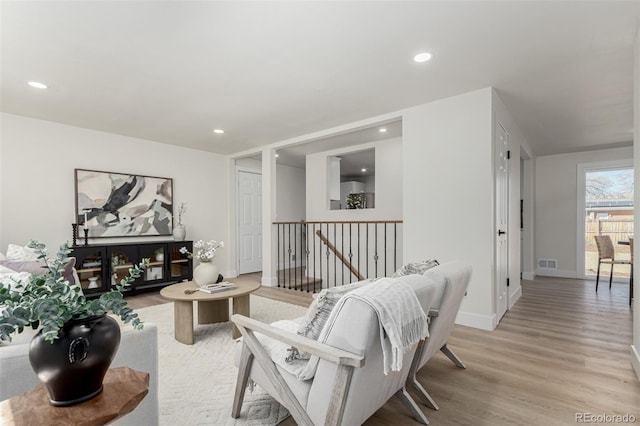 living room featuring light wood-style floors, baseboards, visible vents, and recessed lighting