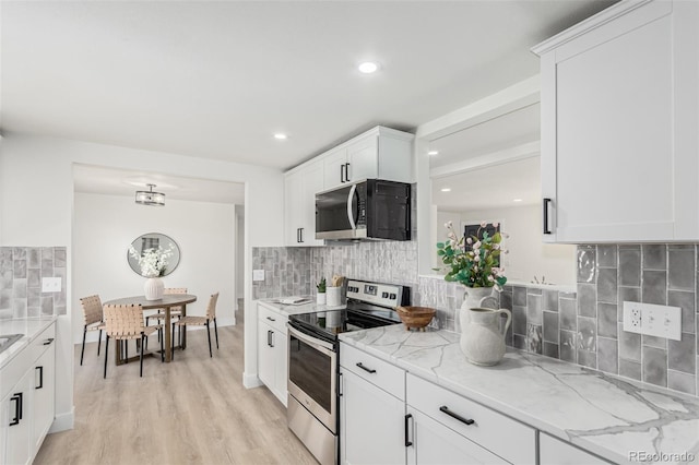 kitchen featuring light wood-style flooring, stainless steel electric stove, white cabinets, backsplash, and light stone countertops