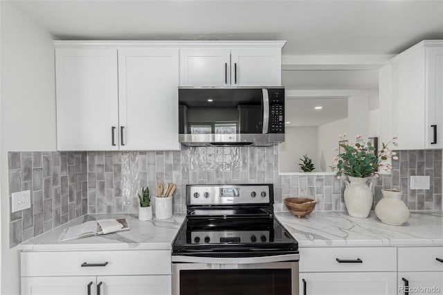 kitchen featuring stainless steel appliances, white cabinets, light stone counters, and decorative backsplash