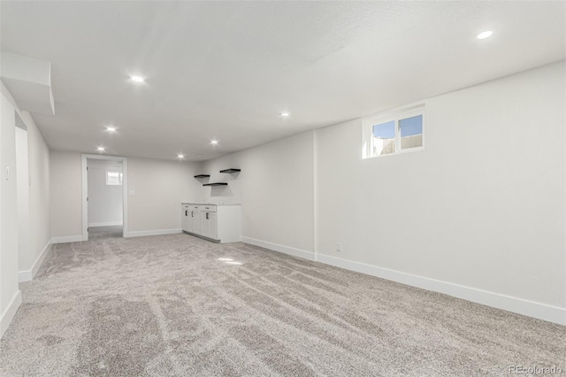 below grade area with light carpet, baseboards, and recessed lighting