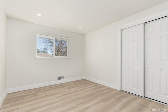 unfurnished bedroom with baseboards, visible vents, light wood finished floors, and a closet